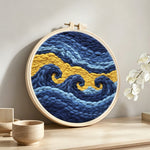 Abstract blue and gold waves punch needle artwork displayed on a table