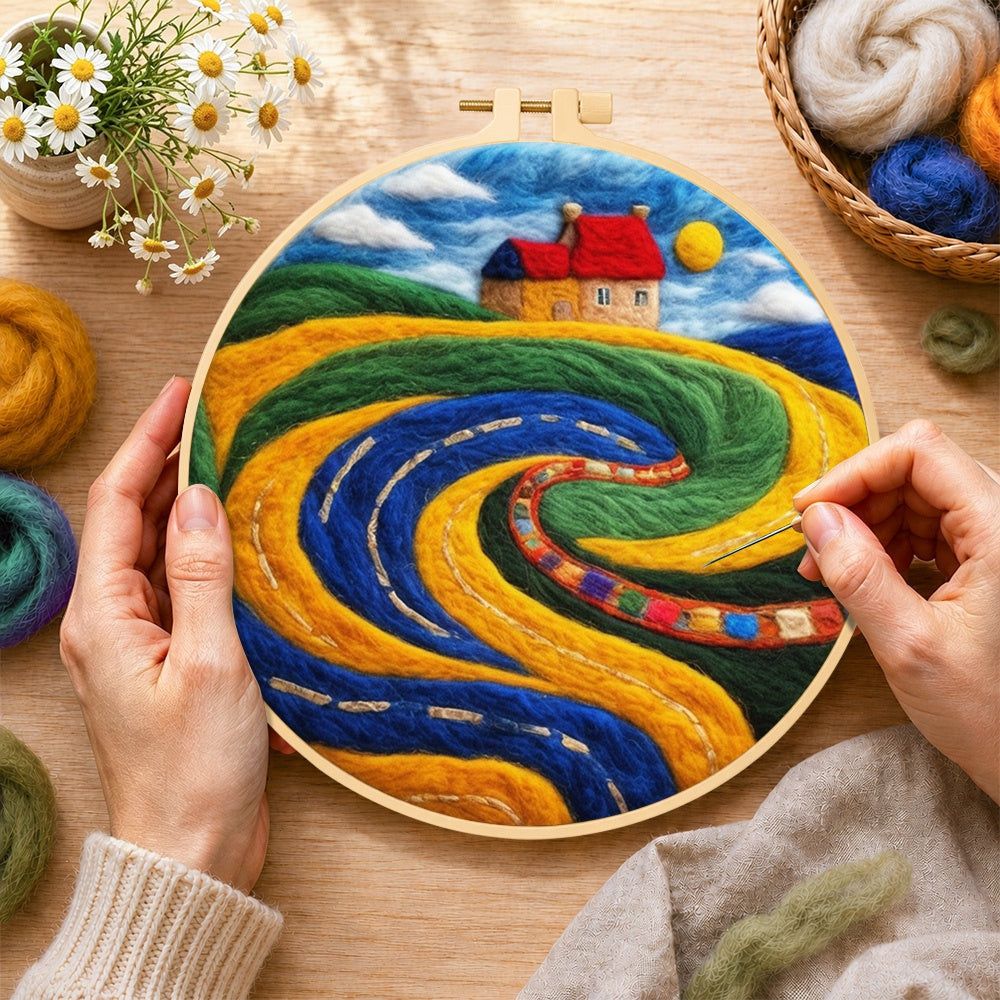 Creating the abstract swirling fields and red roof cottage wool painting by hand with a felting needle