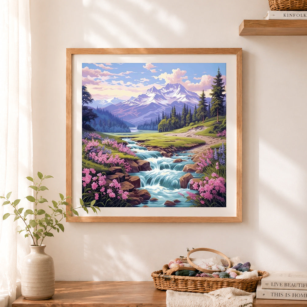 Finished alpine river with pink wildflowers cross stitch artwork displayed as home decor