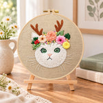 Antler flower kitten embroidery kit finished hoop displayed on a wooden stand as cozy tabletop decor