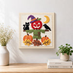 Finished apple scarecrow scene artwork displayed on a wall