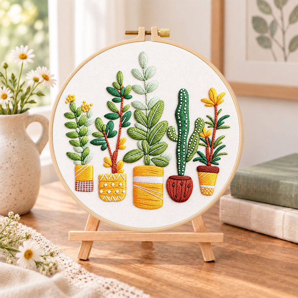 Assorted houseplants embroidery kit finished hoop displayed on a wooden stand as cozy tabletop decor
