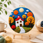 Finished autumn fairy tale tree and house needle felting displayed on a wooden easel