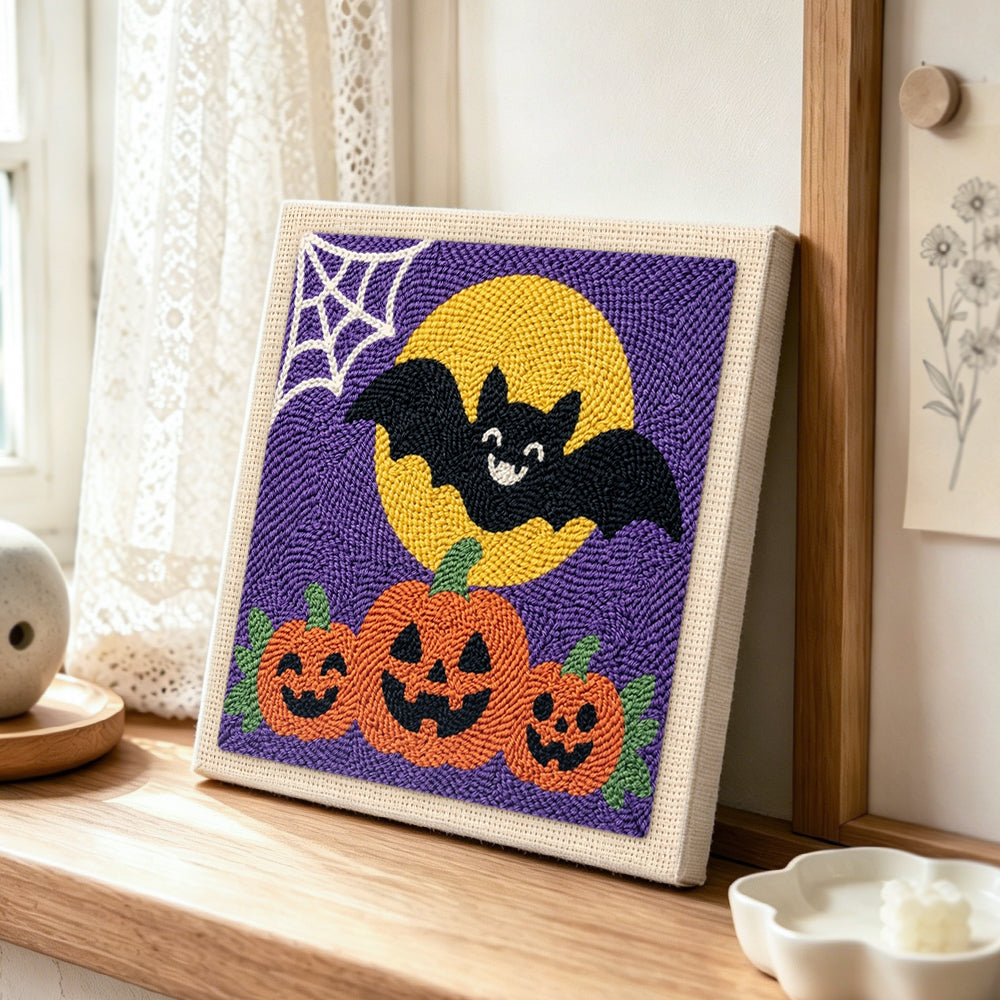 Bat with pumpkins punch needle artwork displayed on a table