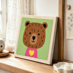 Bear with yellow heart punch needle artwork displayed on a table