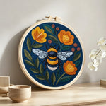 Bee and orange flowers punch needle artwork displayed on a table