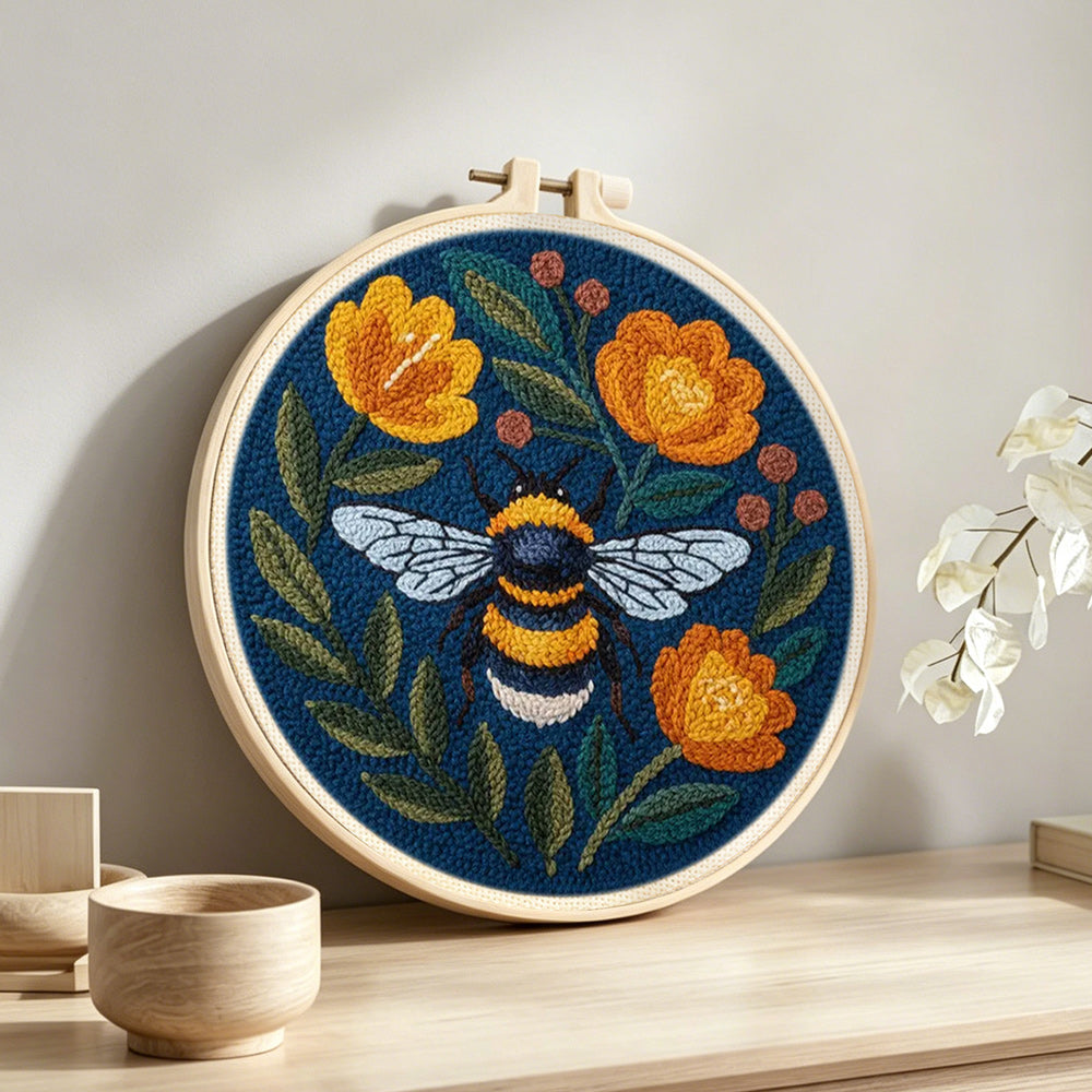 Bee and orange flowers punch needle artwork displayed on a table