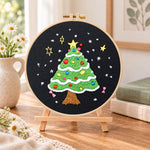 Black background tree embroidery kit finished hoop displayed on a wooden stand as cozy tabletop decor