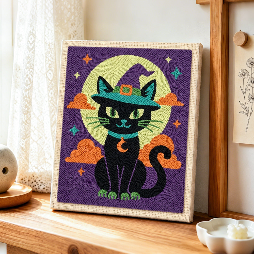 Black cat beneath moon punch needle artwork displayed on a table