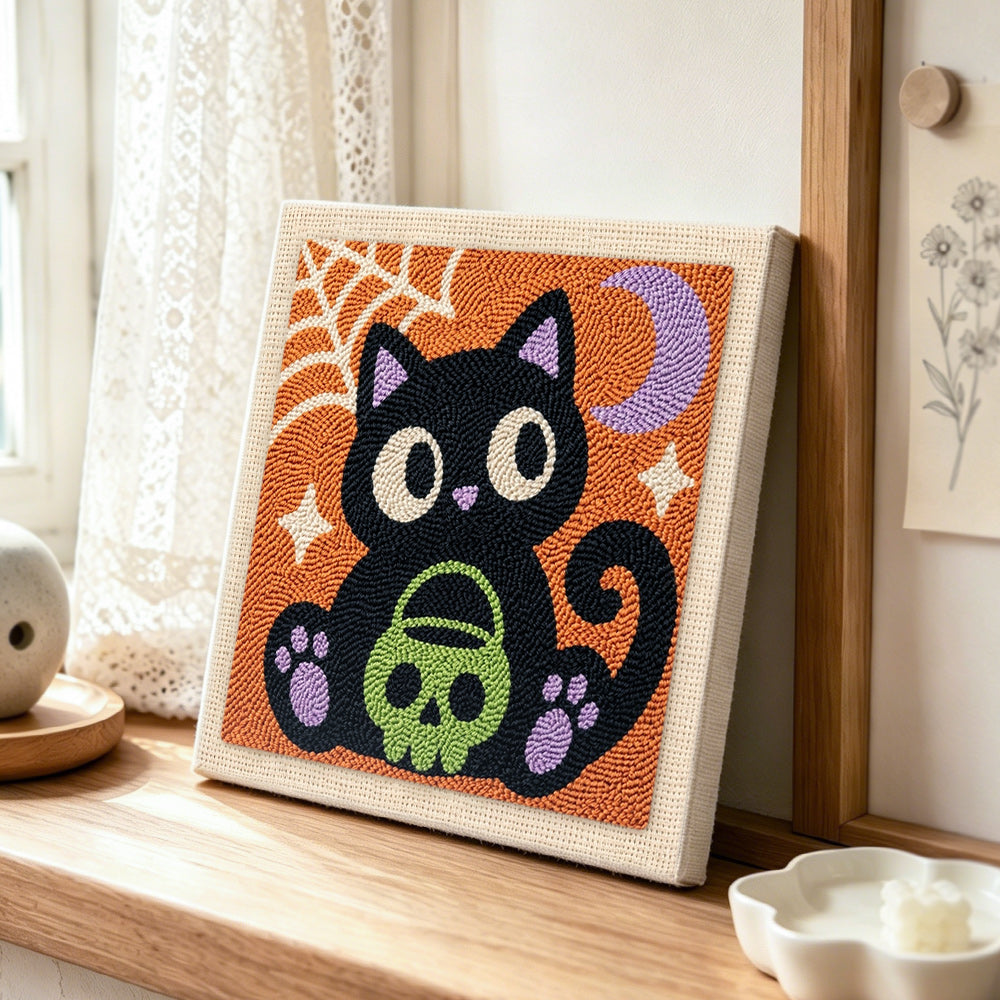 Black cat holding skull treat bucket punch needle artwork displayed on a table