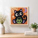 Finished black cat holding skull treat bucket artwork displayed on a wall