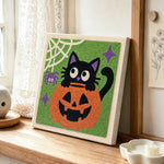 Black cat in pumpkin punch needle artwork displayed on a table