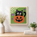 Finished black cat in pumpkin artwork displayed on a wall