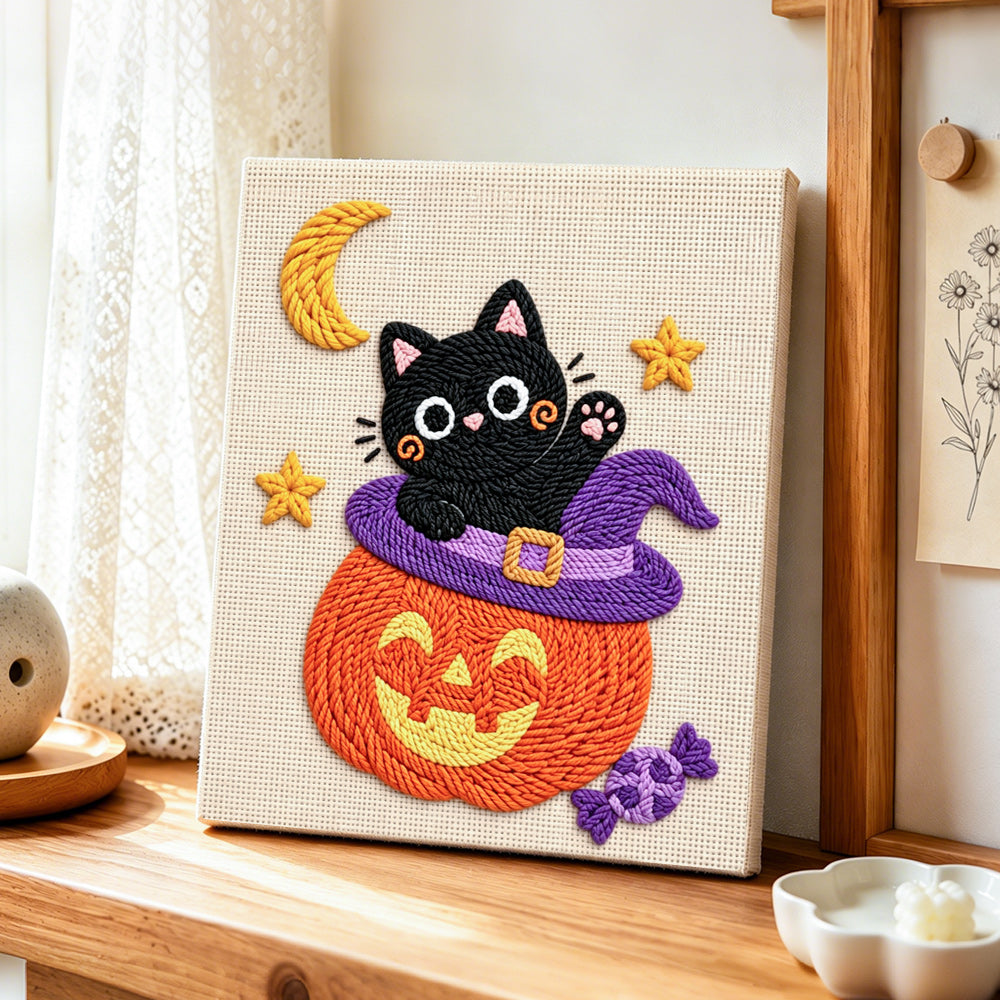 Black cat inside pumpkin hat punch needle artwork displayed on a table