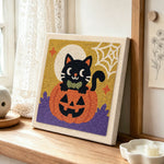 Black cat on pumpkin punch needle artwork displayed on a table