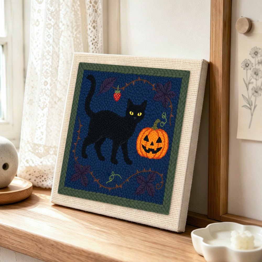 Black cat pumpkin art punch needle artwork displayed on a table