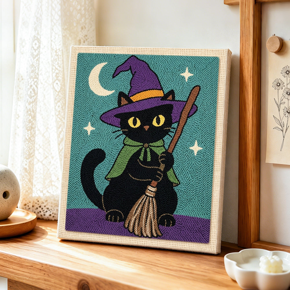 Black cat with broom punch needle artwork displayed on a table