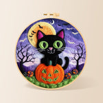 Black cat with green eyes on pumpkin needle felting kit for beginners with a round wooden frame