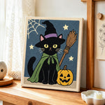 Black cat with pumpkin punch needle artwork displayed on a table