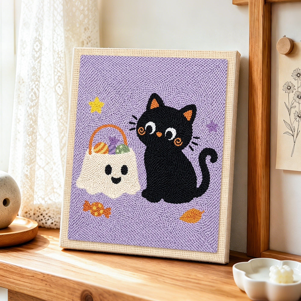 Black cat with trick‑or‑treat bag punch needle artwork displayed on a table