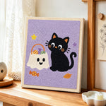 Black cat with trick‑or‑treat bag punch needle artwork displayed on a table