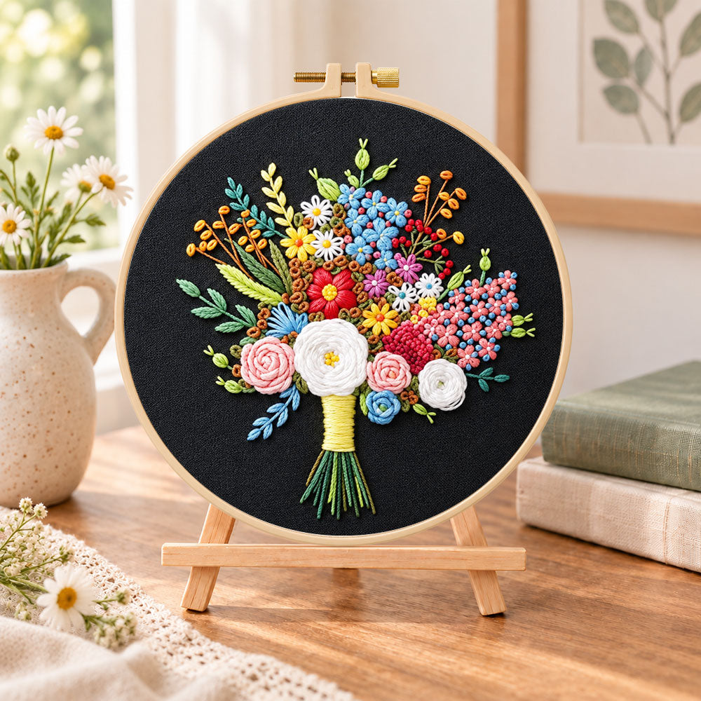 Black fabric flower bouquet embroidery kit finished hoop displayed on a wooden stand as cozy tabletop decor