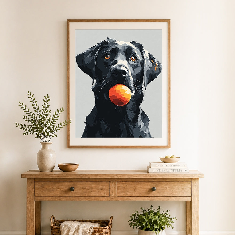 Finished black lab with orange ball cross stitch artwork displayed as home decor