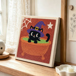 Black witch cat in cauldron punch needle artwork displayed on a table