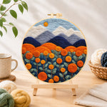 Finished blooming orange roses and mountains needle felting displayed on a wooden easel
