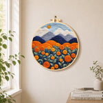 Blooming orange roses and mountains needle felt wall art displayed in a bright home interior
