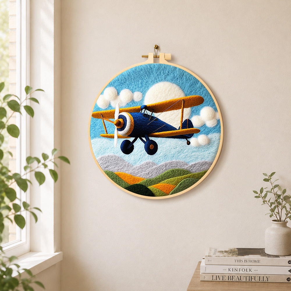 Blue biplane flying needle felt wall art displayed in a bright home interior