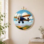 Blue biplane flying needle felt wall art displayed in a bright home interior