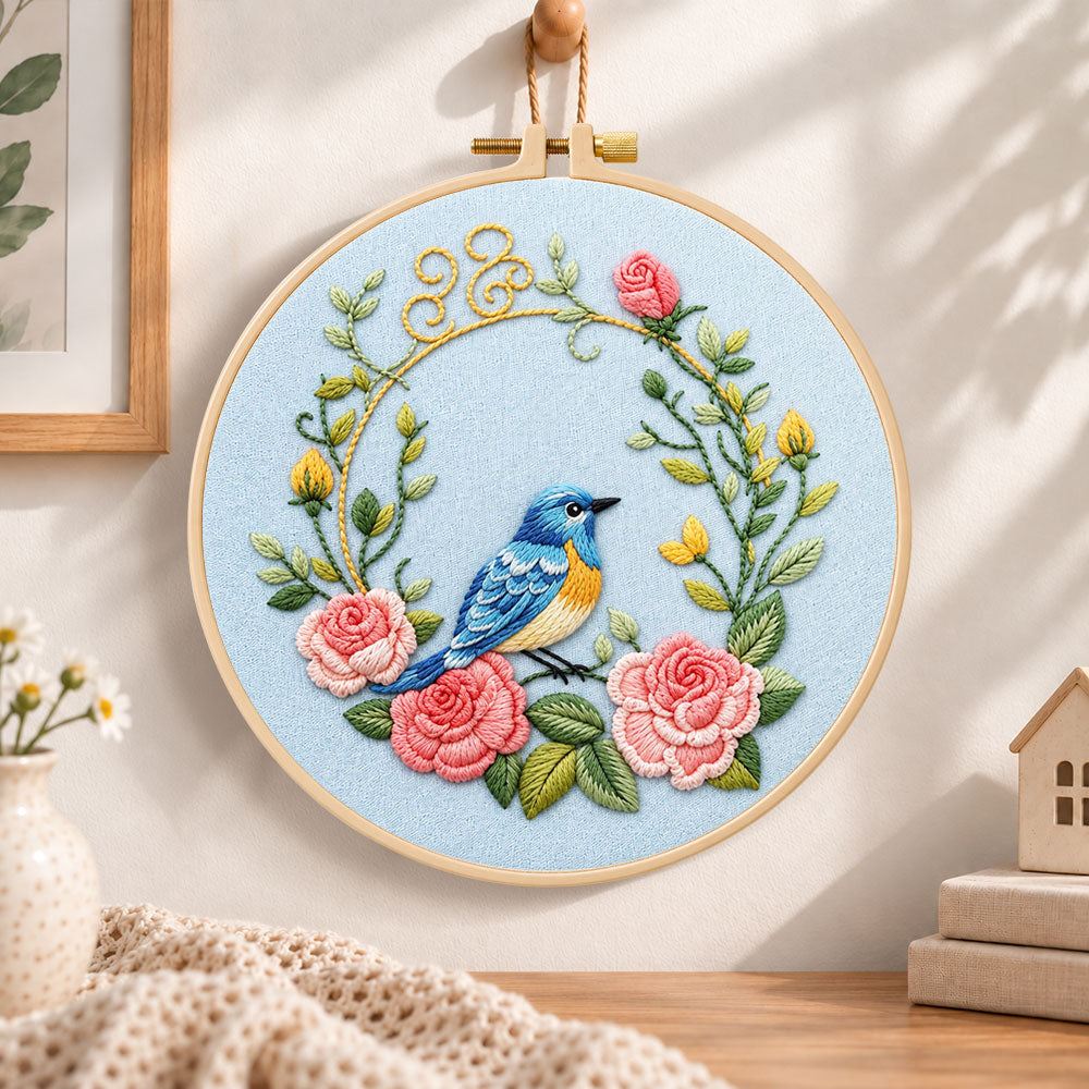 Blue bird inside pink rose wreath embroidery hoop wall art displayed as warm and cozy handmade home decor