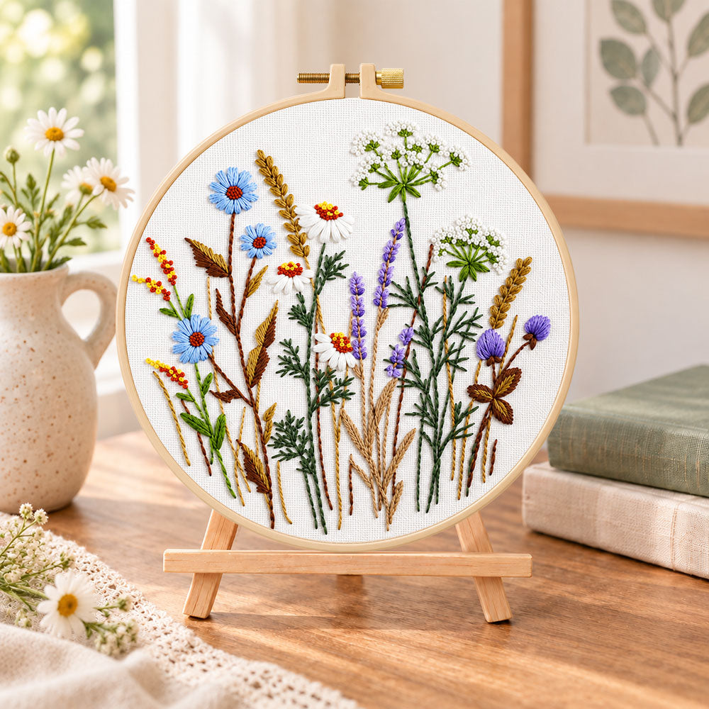 Blue cornflower meadow embroidery kit finished hoop displayed on a wooden stand as cozy tabletop decor