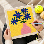 Creating handmade blue flowers in a pink vase punch needle artwork