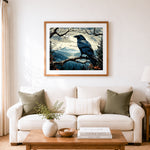 Finished blue raven on bare branch in mountain landscape cross stitch artwork displayed as home decor
