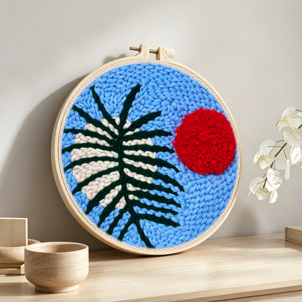 Blue sky botanical with red sun punch needle artwork displayed on a table