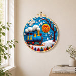 Blue winter train with swirling sun needle felt wall art displayed in a bright home interior