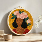 Bold woman with pink floral crown punch needle artwork displayed on a table