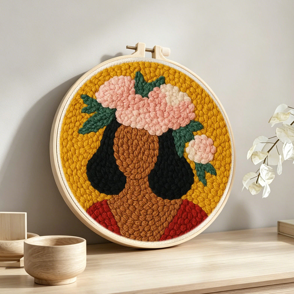 Bold woman with pink floral crown punch needle artwork displayed on a table