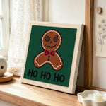 Bow tie gingerbread man art punch needle artwork displayed on a table
