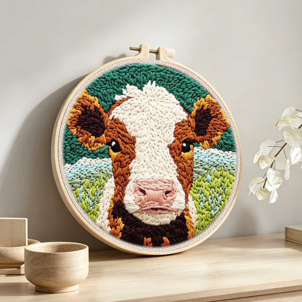 Brown and white cow face punch needle artwork displayed on a table