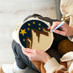 Creating handmade brown and white snowy mountains under a starry sky punch needle artwork