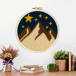 Finished brown and white snowy mountains under a starry sky artwork displayed on a wall