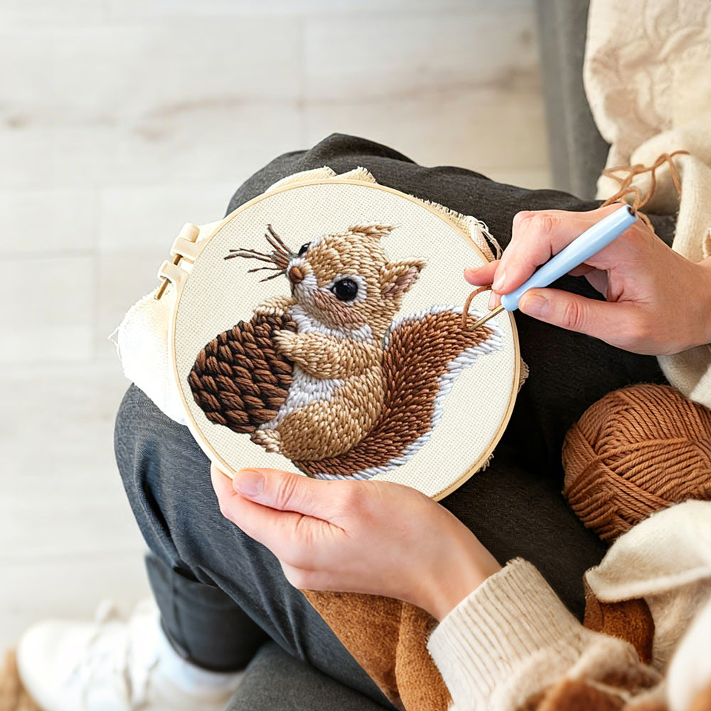 Creating handmade brown squirrel holding pine cone punch needle artwork