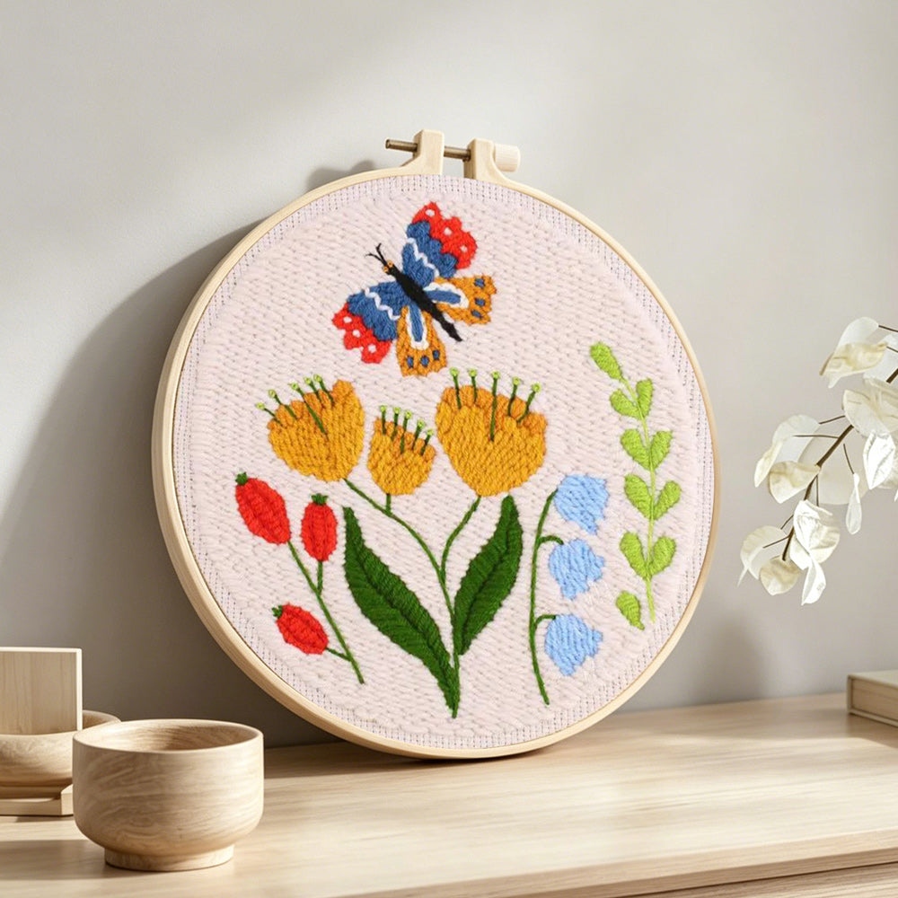 Butterfly and garden wildflowers punch needle artwork displayed on a table