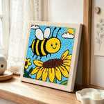 Buzzing bee with giant sunflower punch needle artwork displayed on a table