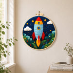 Cartoon rocket launch needle felt wall art displayed in a bright home interior
