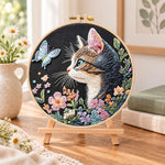 Cat and blue butterfly embroidery kit finished hoop displayed on a wooden stand as cozy tabletop decor