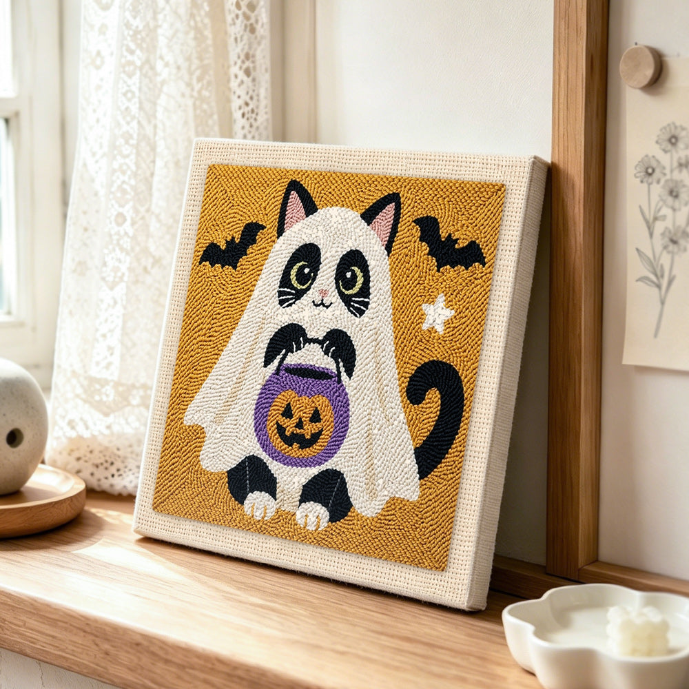 Cat ghost with pumpkin bucket punch needle artwork displayed on a table